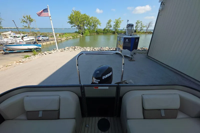 Slide: The Image of Pontoon boat docked near a lake with American flag and trees in the background. - 15