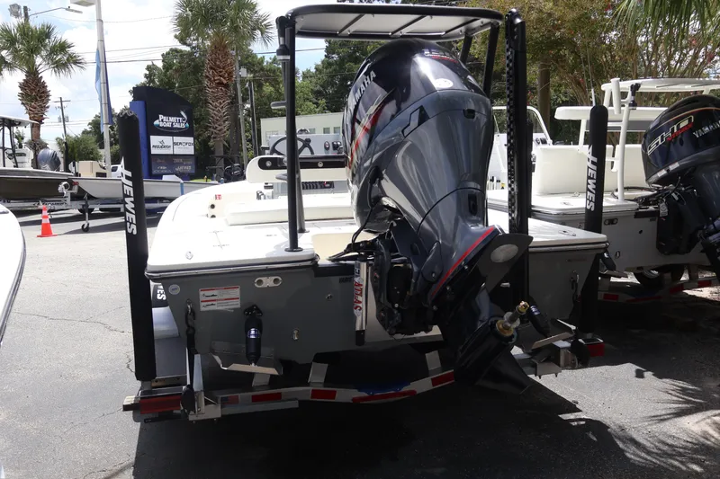 Slide: The Image of 2026 Hewes Redfisher 18 boat with Yamaha outboard motor, parked near a fence. - 6