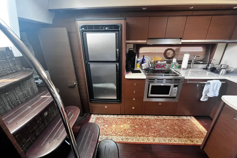 Slide: The Image of Interior of 2012 Sea Ray 500 Sundancer yacht kitchen with modern appliances and wooden cabinetry. - 22