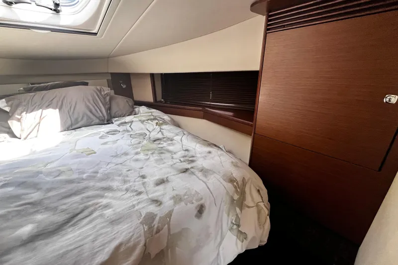 Slide: The Image of Cozy cabin interior of 2012 Sea Ray 500 Sundancer with bed and wooden cabinetry. - 26