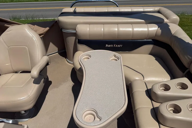 Slide: The Image of 2004 Parti Kraft Admiral 220 RE pontoon boat interior with beige seating and table. - 11