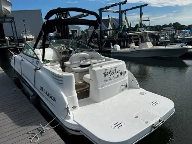 Slide: The Image of 2010 Larson Cabrio 274 boat docked at marina, featuring spacious deck and seating. - 18