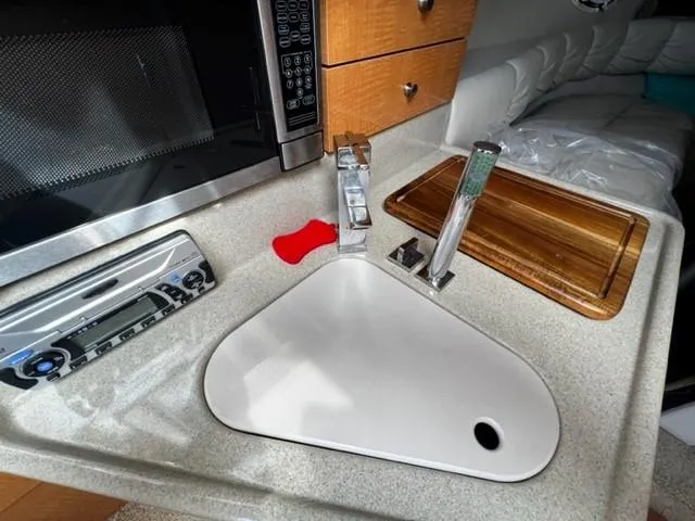 Slide: The Image of 2010 Larson Cabrio 274 kitchen area with sink, microwave, and cutting board. - 23