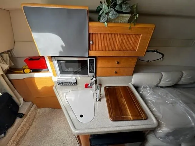 Slide: The Image of 2010 Larson Cabrio 274 boat interior with kitchenette, sink, microwave, and wooden cutting board. - 30