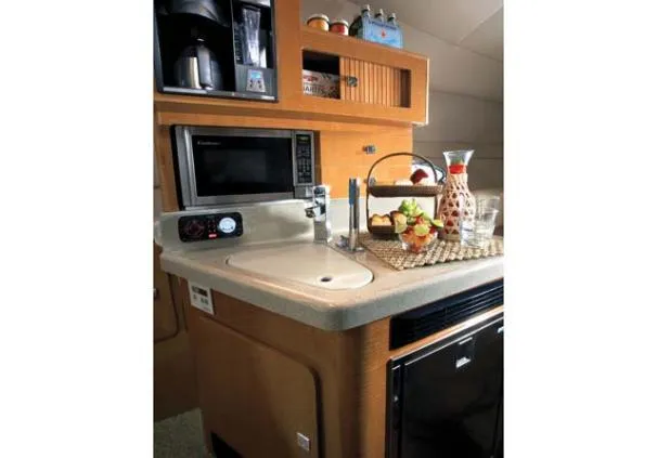 Slide: The Image of Compact kitchen in 2010 Larson Cabrio 274 boat with microwave, sink, and countertop accessories. - 7