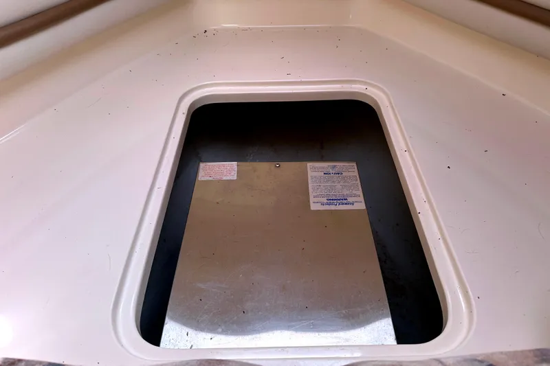 Slide: The Image of Storage compartment of a 2000 Grady-White Express 265 boat, featuring a metal cover. - 28