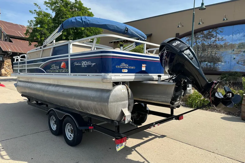 Slide: The Image of 2015 Sun Tracker Fishin' Barge 20 DLX pontoon boat on trailer, parked outdoors. - 2