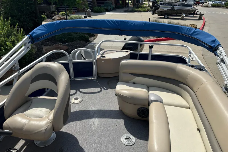 Slide: The Image of 2015 Sun Tracker Fishin' Barge 20 DLX interior with beige seating and blue canopy. - 4