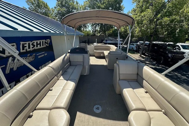 Slide: The Image of 2017 Ranger Reata 220C pontoon boat with beige seating and canopy in outdoor setting. - 12