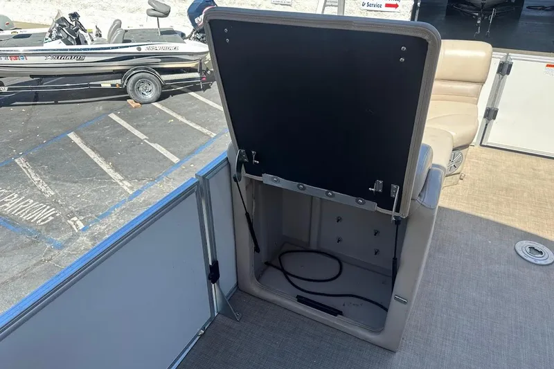 Slide: The Image of 2017 Ranger Reata 220C boat interior with open storage compartment, docked beside another boat. - 27