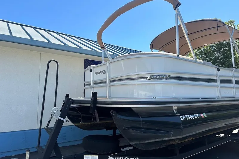 Slide: The Image of 2017 Ranger Reata 220C pontoon boat on trailer, parked beside a building. - 4
