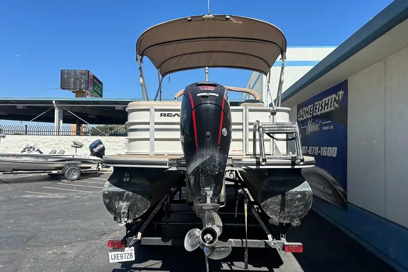 Slide: The Image of 2017 Ranger Reata 220C pontoon boat with canopy and outboard motor in parking lot. - 8