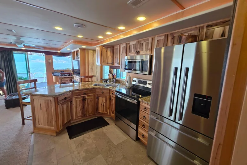 Slide: The Image of Luxurious kitchen in 2015 Sailabration 64 houseboat with modern appliances and wood cabinetry. - 21