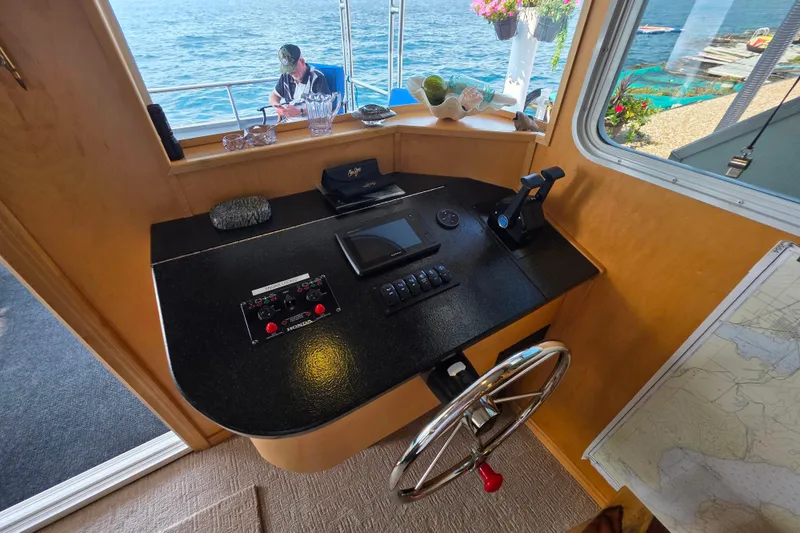 Slide: The Image of Helm of 2015 Sailabration 64 houseboat with steering wheel and control panel, overlooking water. - 22