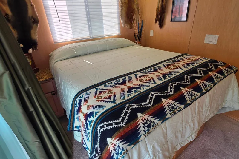 Slide: The Image of Cozy bedroom in 2015 Sailabration 64 houseboat with patterned blanket and natural light. - 34