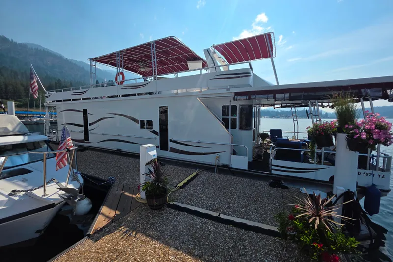 Slide: The Image of Houseboat docked on a lake, Sailabration 64 model, 2015, with red canopy and floral decorations. - 6