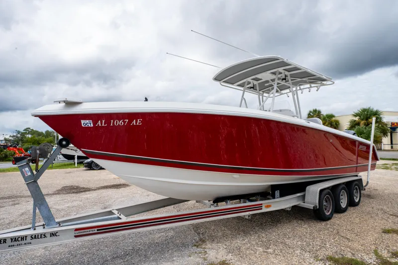 Slide: The Image of Red 2004 Jupiter 27fs boat on trailer, parked outdoors under cloudy sky. - 10