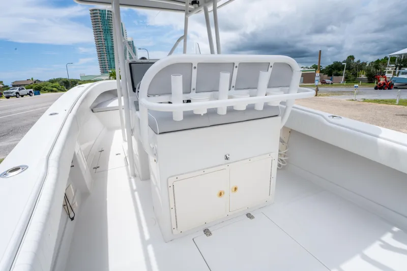 Slide: The Image of 2004 Jupiter 27fs boat interior with seating and storage, docked near a road. - 13