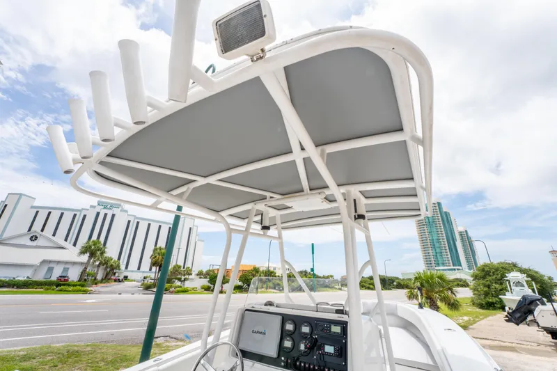 Slide: The Image of 2004 Jupiter 27fs boat with T-top and console, parked near modern buildings. - 20