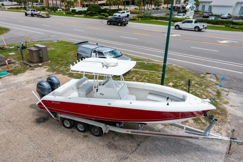 Slide: The Image of Red and white 2004 Jupiter 27fs boat on trailer, parked near a road. - 28