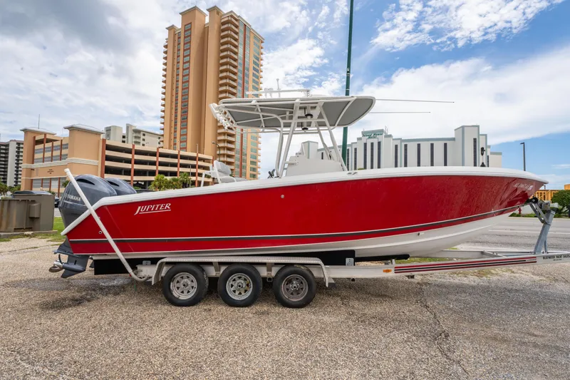 Slide: The Image of Red 2004 Jupiter 27fs boat on trailer, city buildings in background, partly cloudy sky. - 5