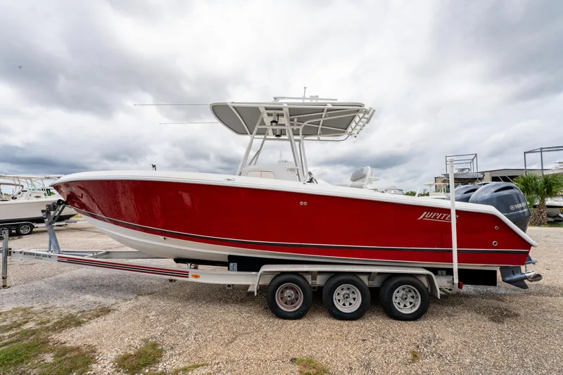Slide: The Image of 2004 Jupiter 27fs boat with red hull on a trailer, cloudy sky background. - 9