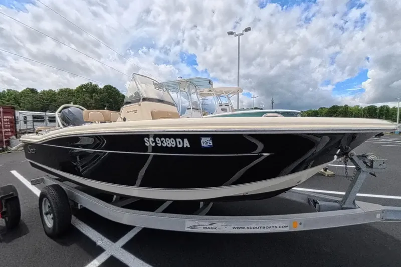 The Image of 2014 Scout 195 Sportfish boat on trailer, parked outdoors under cloudy sky. - 0