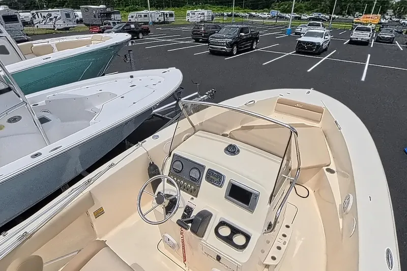 Slide: The Image of 2014 Scout 195 Sportfish boat in parking lot, featuring helm and seating area. - 2