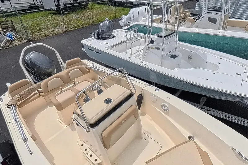 Slide: The Image of 2014 Scout 195 Sportfish boat with beige seating, parked alongside other boats. - 6