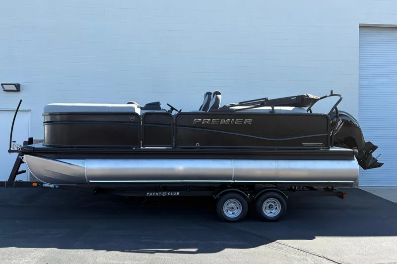 The Image of 2026 Premier 210 Sunsation RF pontoon boat on trailer, parked outdoors. - 0