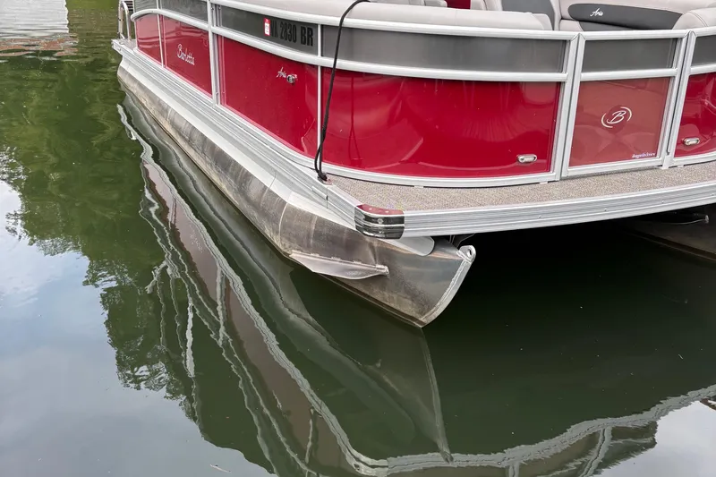 Slide: The Image of 2025 Barletta ARIA 22QC pontoon boat with red exterior on calm water. - 4