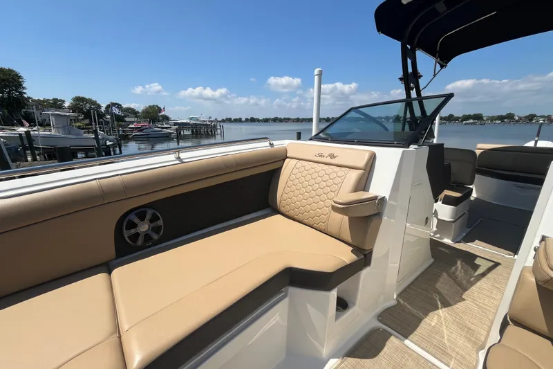 Slide: The Image of 2021 Sea Ray SDX 270 Outboard boat interior with tan seating, docked by a serene lake. - 19