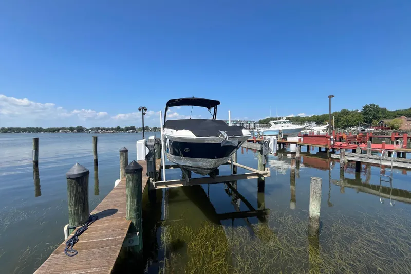 Slide: The Image of 2021 Sea Ray SDX 270 Outboard on lift at marina dock, clear blue sky. - 2