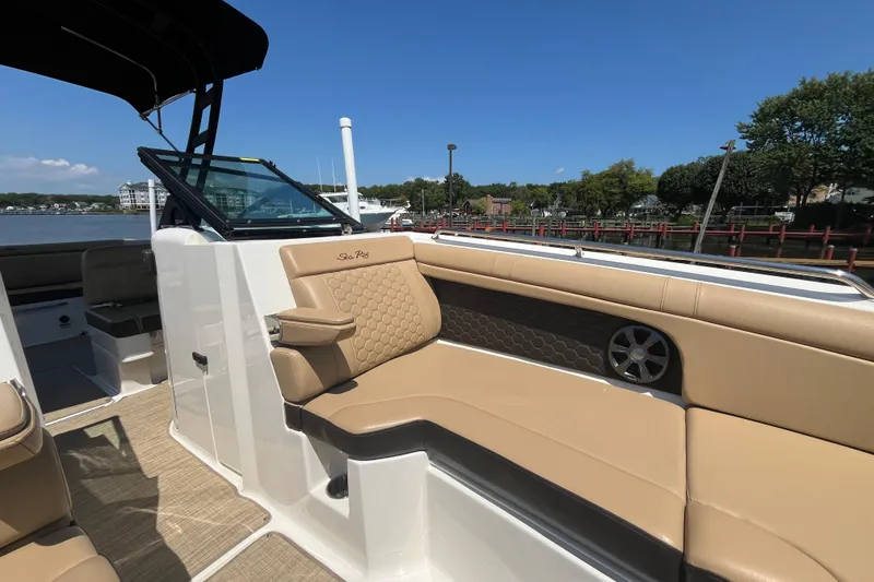 Slide: The Image of 2021 Sea Ray SDX 270 Outboard boat interior with tan seating and scenic waterfront view. - 20