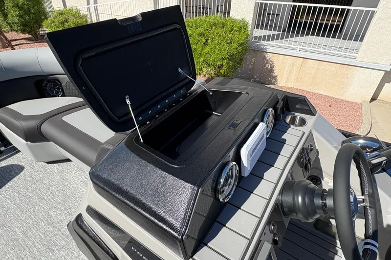 Slide: The Image of 2026 Premier 210 Sunsation RF boat dashboard with open storage compartment and steering wheel. - 10