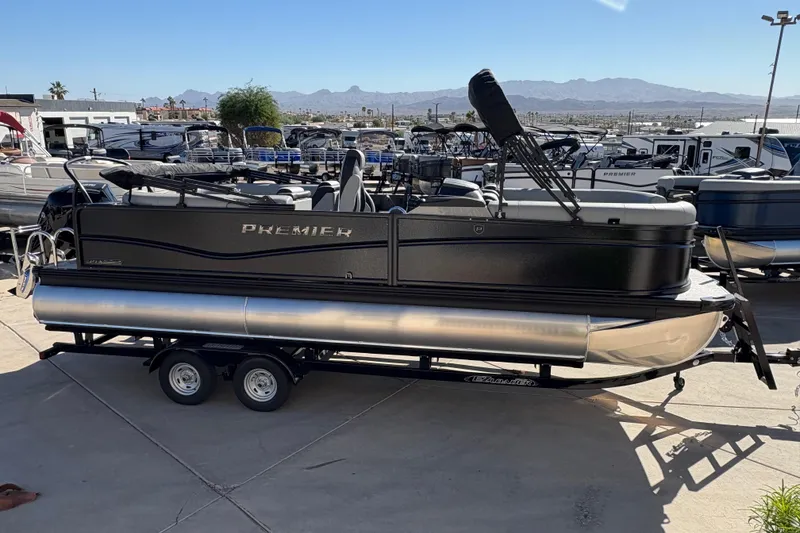 Slide: The Image of 2026 Premier 230 SunSation RF pontoon boat on trailer, parked outdoors with mountains in background. - 5