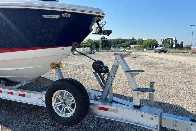 Slide: The Image of 2023 Chaparral 307 SSX boat on trailer, parked in a gravel lot under clear blue sky. - 22