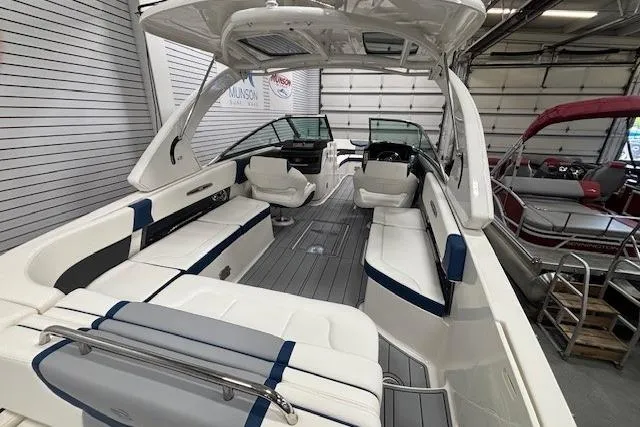 Slide: The Image of 2023 Chaparral 307 SSX boat interior with white and blue seating in a showroom. - 32