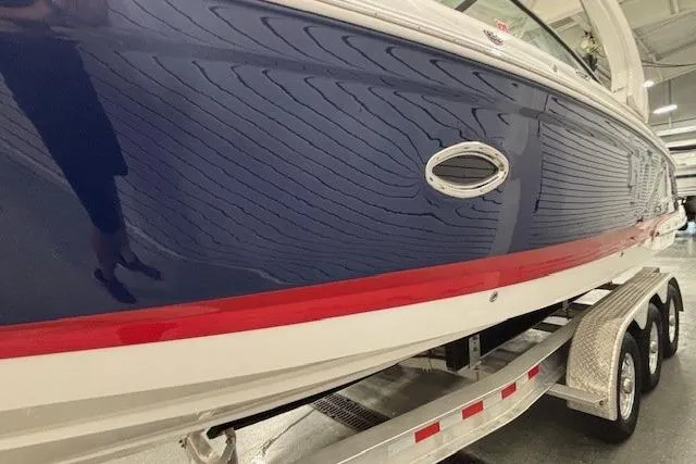 Slide: The Image of 2023 Chaparral 307 SSX boat with blue and red detailing on a trailer. - 56