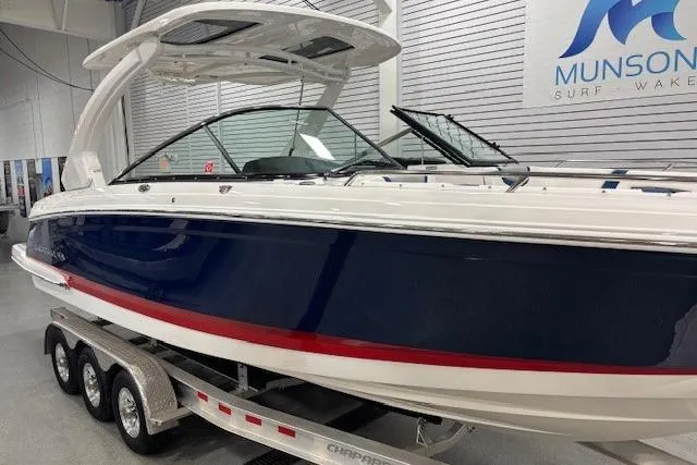 Slide: The Image of 2023 Chaparral 307 SSX boat on trailer in showroom, blue and white exterior. - 68