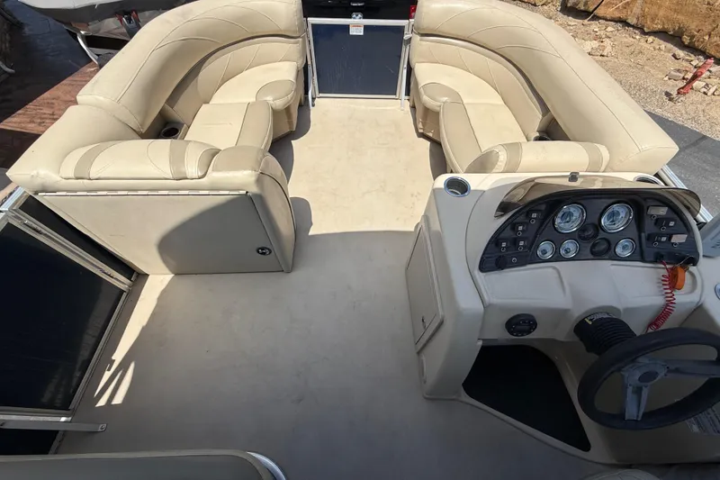 Slide: The Image of 2019 SunChaser Geneva Cruise 22 LR PSB pontoon boat interior with beige seating and control panel. - 16