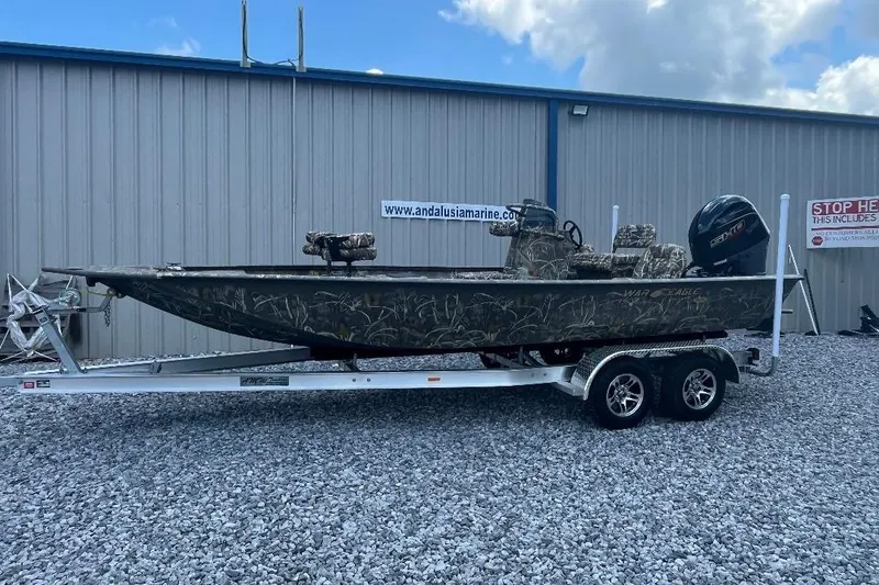 Slide: The Image of 2026 War Eagle 2170 Blackhawk boat on trailer, parked outside a metal building. - 1