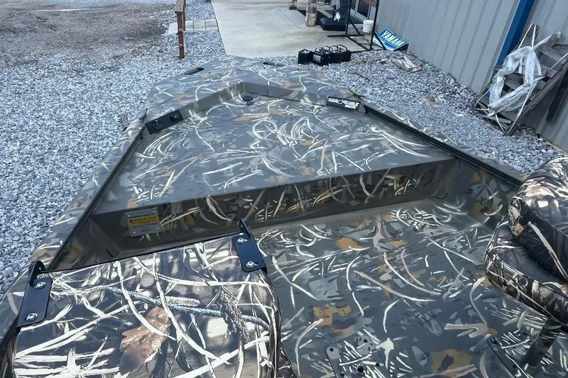 Slide: The Image of 2026 War Eagle 2170 Blackhawk boat with camouflage pattern on gravel surface. - 17