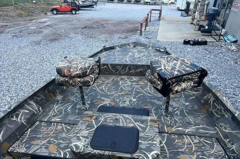 Slide: The Image of 2026 War Eagle 2170 Blackhawk boat with camouflage seating and deck, parked on gravel. - 20