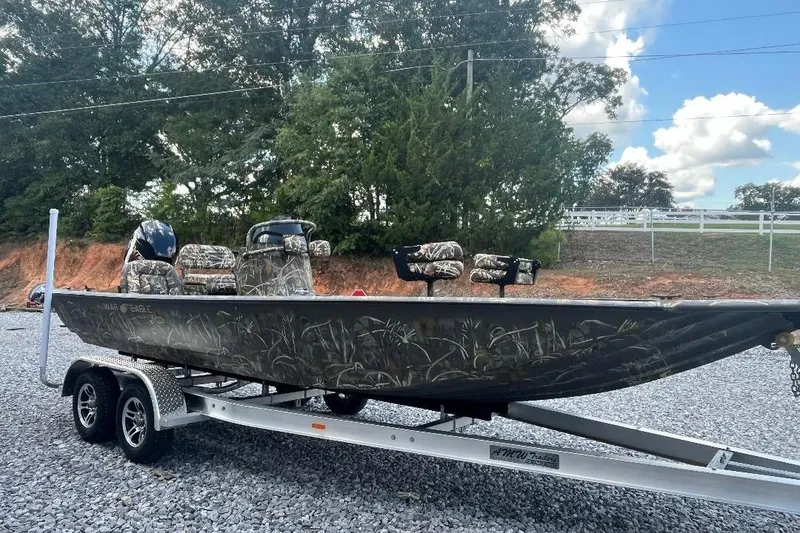 Slide: The Image of 2026 War Eagle 2170 Blackhawk boat on trailer, camo design, parked outdoors. - 4