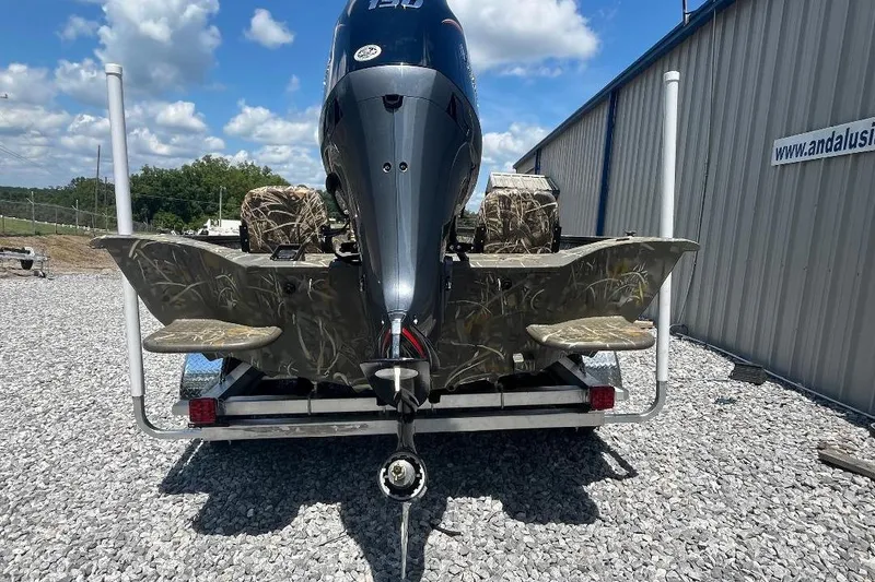 Slide: The Image of 2026 War Eagle 2170 Blackhawk boat with camo design, parked on gravel near a building. - 9