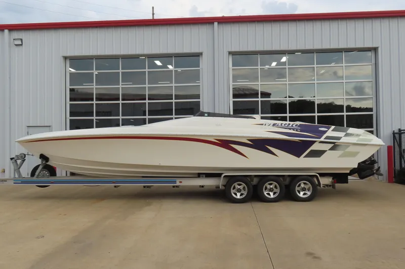 The Image of 1998 Magic 34 Sorcerer speedboat on trailer, parked outside a garage. - 1