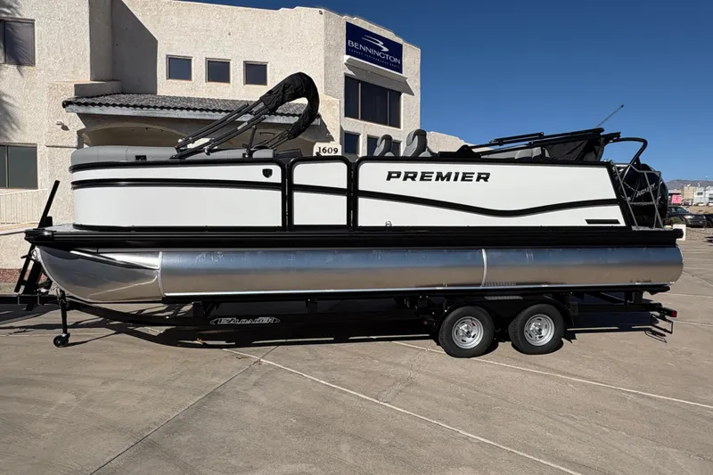 The Image of 2026 Premier 230 Sunsation RL pontoon boat on trailer, parked outside a building. - 0