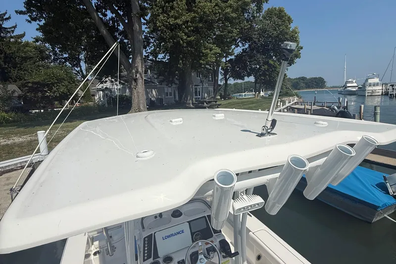 Slide: The Image of 2022 Robalo 226 Cayman boat with rod holders, docked near a scenic waterfront. - 19