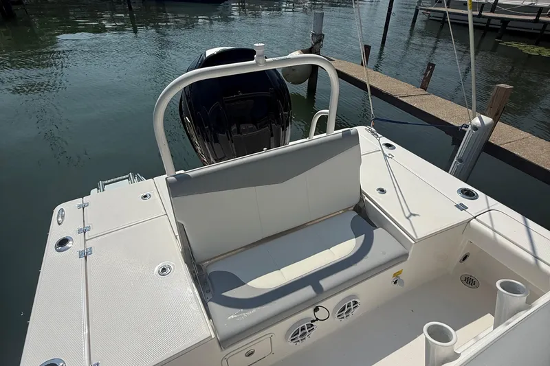 Slide: The Image of 2022 Robalo 226 Cayman boat interior with seating and motor, docked on calm water. - 9